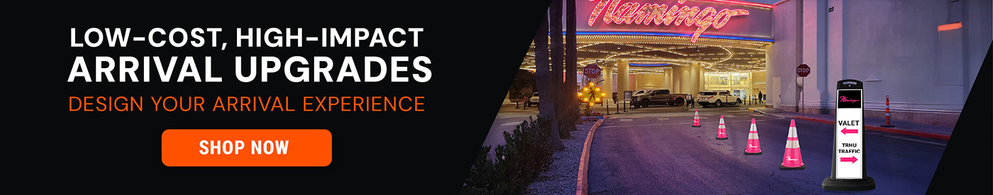 Valet arrival area at night featuring pink traffic cones and a branded SD2K valet wayfinding sign directing vehicles for valet and thru traffic